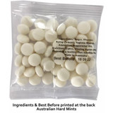 A clear bag containing white mints with visible round discs. The bag has a branding logo and ingredient details on the back.