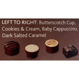 A box of four chocolates in brown and white: Butterscotch Cup, Cookies & Cream, Baby Cappuccino, Dark Salted Caramel.