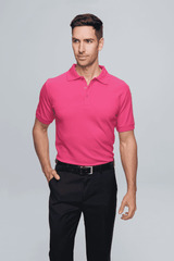 A pink polo shirt worn by a model, styled with black trousers, featuring a collar and short sleeves.