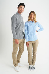 A man and woman model stylish button-up shirts in check and striped patterns, paired with beige pants and casual shoes.