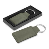 An olive green key ring presented in a black packaging box. It features a metal ring and a rectangular leatherette tag.