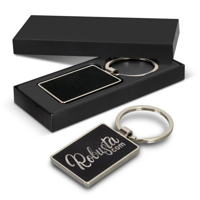 A rectangular key ring with a black texture, presented in a sleek black box, featuring a logo.