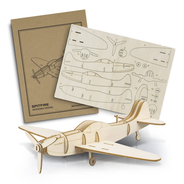A wooden model of a Spitfire aircraft in natural wood finish with assembly parts and instructions.