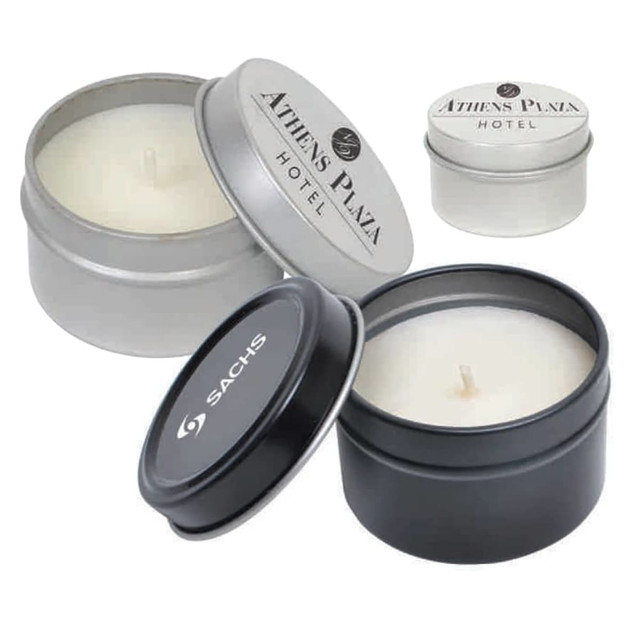 A set of vanilla scented candles in silver and black tin containers, featuring various logos on the lids.