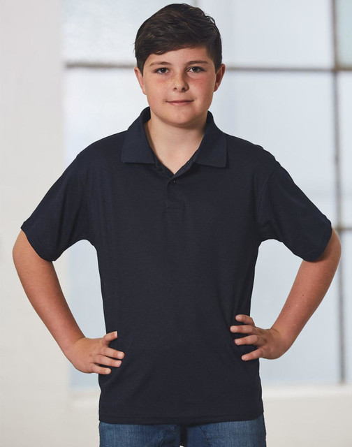 A young boy in a black short-sleeve polo shirt stands confidently with his hands on his hips.