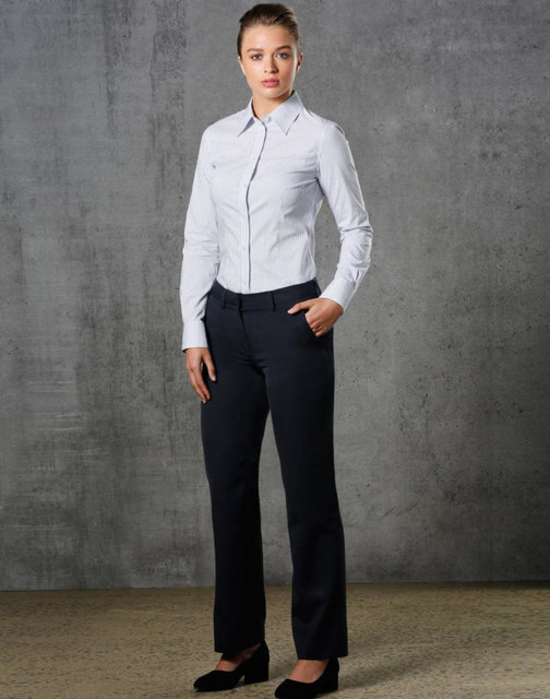A model wearing ladies' permanent press pants in black, paired with a light blue button-up shirt, standing against a textured backdrop.