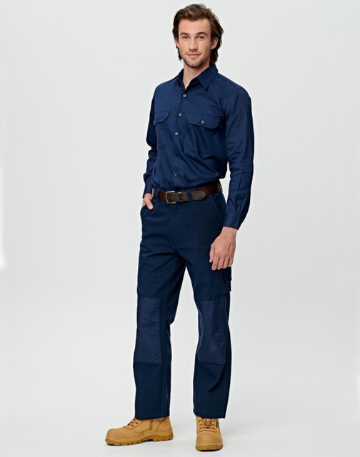 A man wearing beige work pants featuring pockets and reinforced knee patches, paired with a matching long-sleeve shirt.