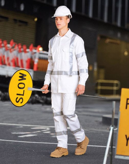A man wearing a white safety shirt and trousers with reflective stripes holds a 'SLOW' sign. He wears a safety helmet.