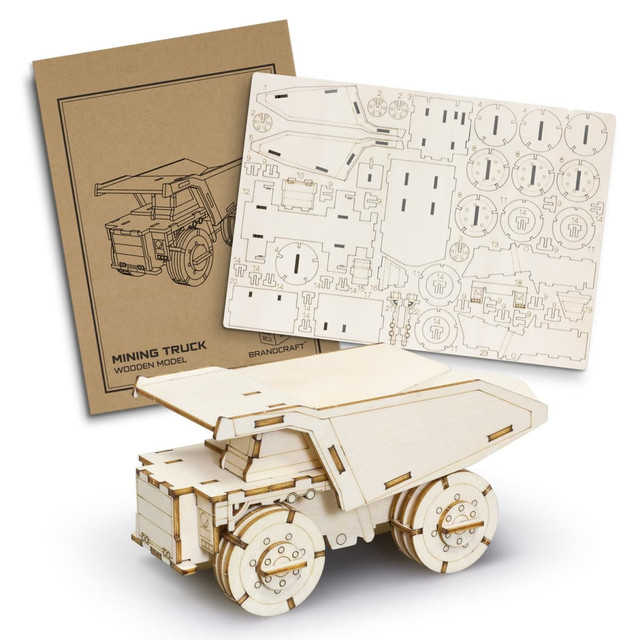 A wooden model of a mining truck in natural wood colour, with accompanying assembly sheets and a branded box.