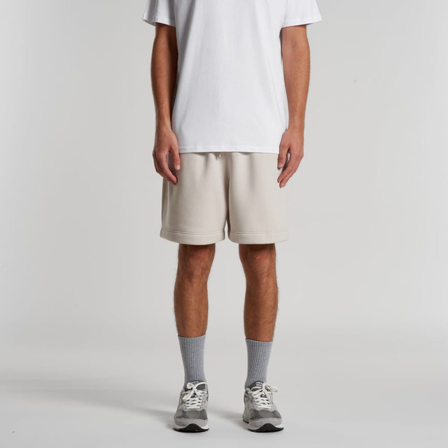 Light beige relaxed track shorts with side pockets, worn by a model standing against a plain background.
