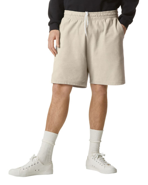 Beige unisex gym shorts with an elastic waistband and side pockets, worn with white sneakers and grey socks.
