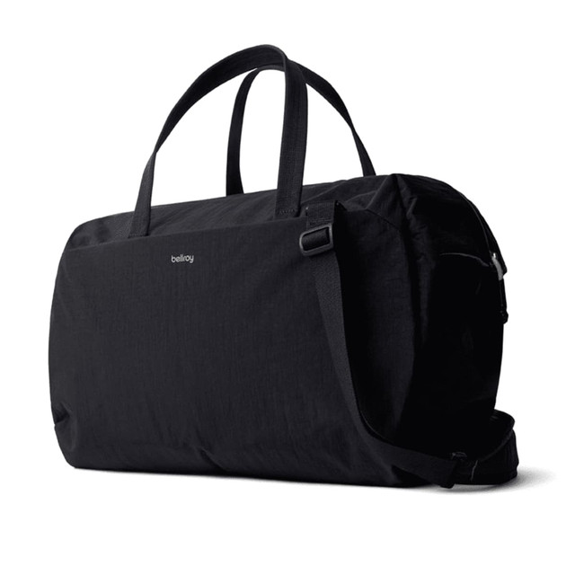 A black duffel bag with two handles and a shoulder strap, featuring a logo.