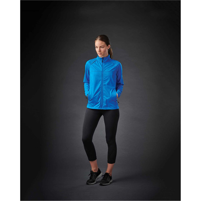 A lightweight softshell jacket in blue, worn by a model, paired with black leggings and shoes.