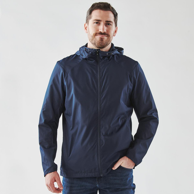 A navy wind jacket features a hood, front zip, and a logo on the chest, worn by a smiling man.