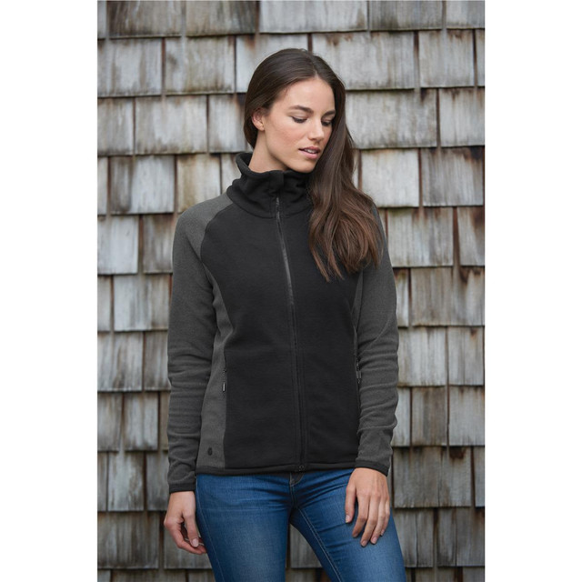 A microfleece jumper in black and grey, featuring a zip front and a high collar, displayed against a wooden background.