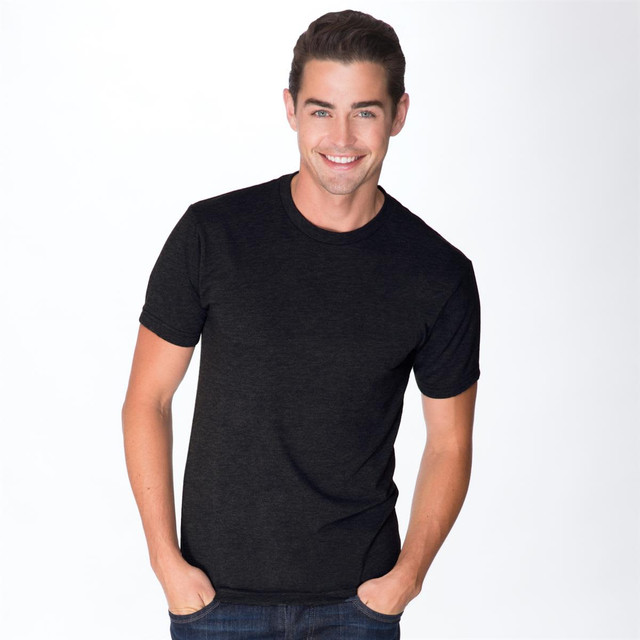 A black tri-blend crew t-shirt featured on a smiling man, with a simple design and a logo present.