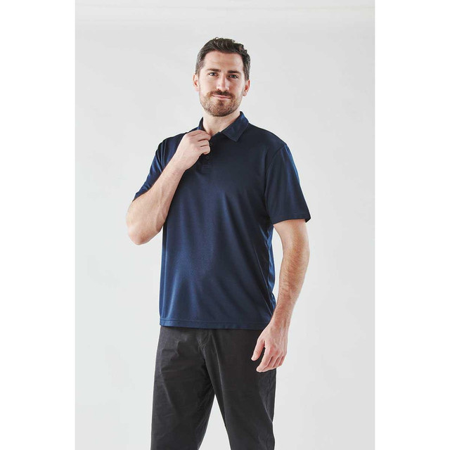 Men's Treeline performance short sleeve polo in navy blue, featuring a collar and a logo. Styled with black trousers.