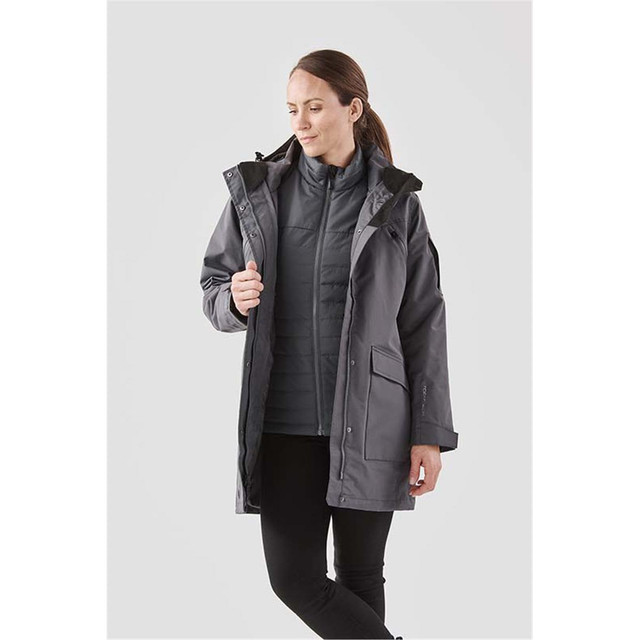 A grey women's 5-in-1 system jacket featuring a hood and multiple pockets, modelled by a woman.