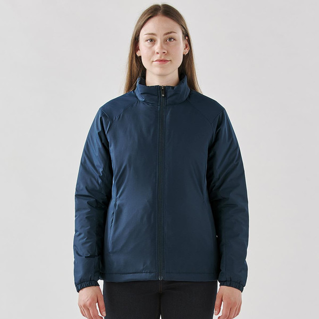 A woman wearing a navy blue thermal jacket with a zip front and a high collar, featuring a small logo.