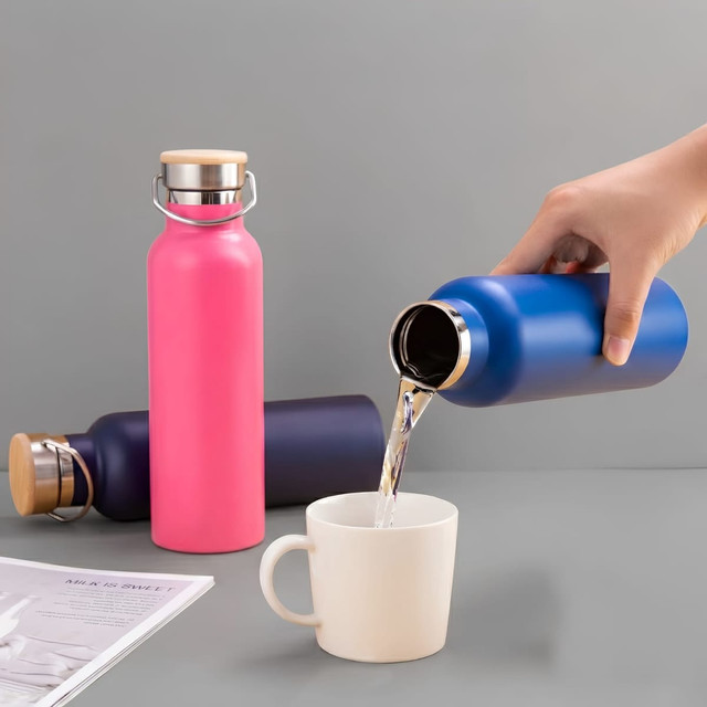 A drink bottle in pink and blue, featuring a sleek design and a metal lid, with liquid being poured into a cup.