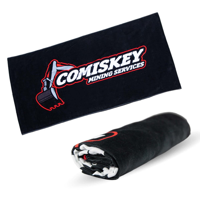 A black beach towel featuring a logo, measuring 75cm x 150cm, prominently displayed when rolled out.