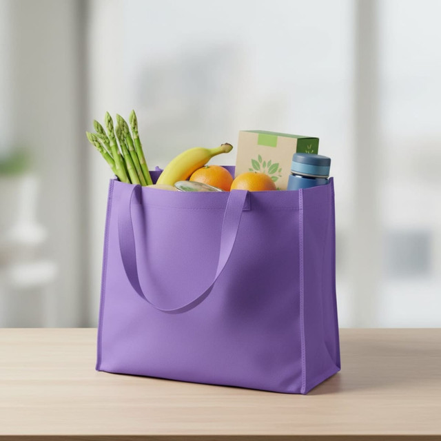 A purple non-woven tote filled with bananas, oranges, asparagus, and a drink bottle. It has two handles.