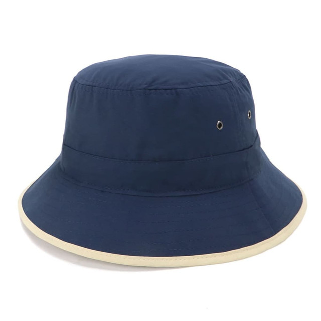 A navy microfibre bucket hat with a cream trim, featuring metal eyelets for ventilation and a simple design.