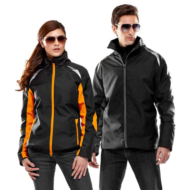 A black jacket with orange accents for men and women, featuring a logo and a stylish design. Both models wear sunglasses.