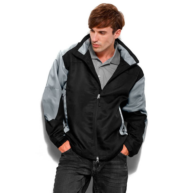 A black and grey jacket with a zip, featuring a logo, worn by a model.