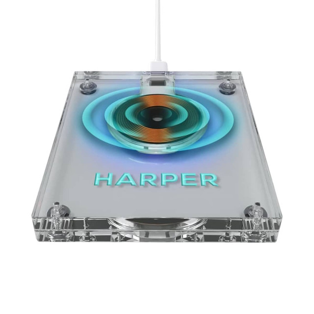 A clear acrylic wireless charger with a circular charging pad in the centre and a prominent logo.