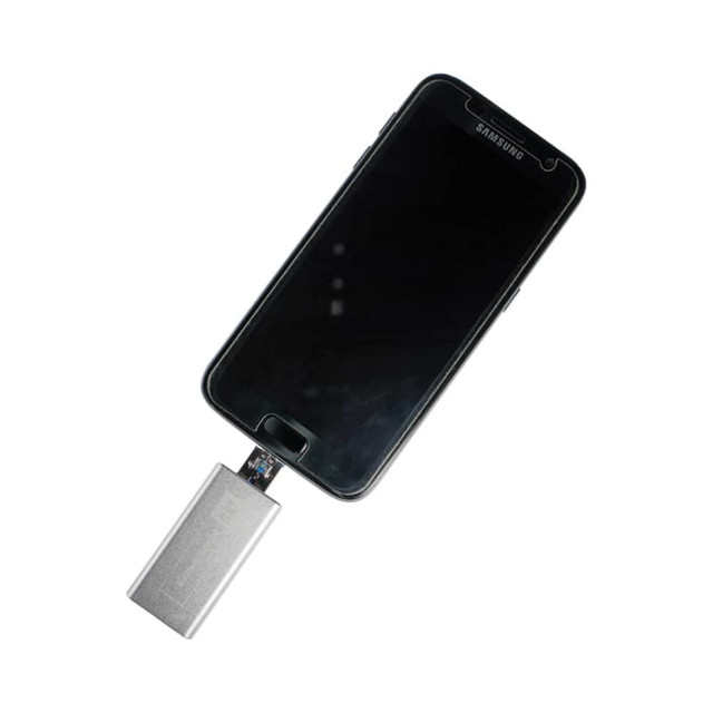 A silver Banion OTG USB 3.0 flash drive connected to a black smartphone. The device has a logo on it.