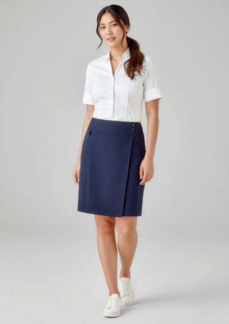A woman wearing a navy skort and a white shirt, standing in a neutral background. The skort features a logo.