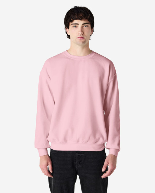 A pink crewneck sweatshirt displayed on a model against a neutral background, featuring long sleeves and a relaxed fit.