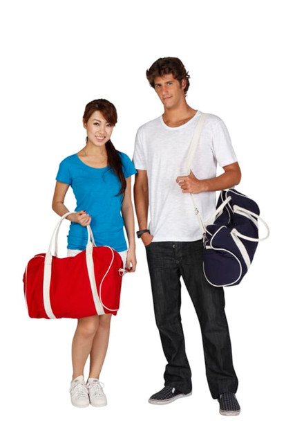 A red duffle bag and a navy bag are held by a woman in a blue shirt and a man in a white shirt. Both bags have branding.