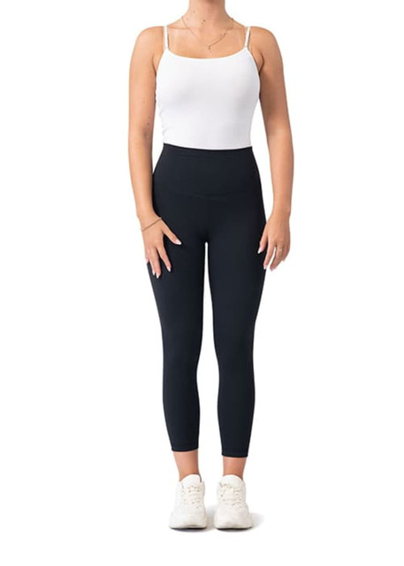Black high-rise full-length leggings paired with a white tank top and white sneakers, featuring a logo.