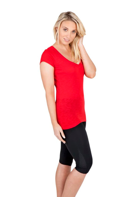 A woman poses in a red V-neck T-shirt paired with black leggings, featuring a logo on the shirt.