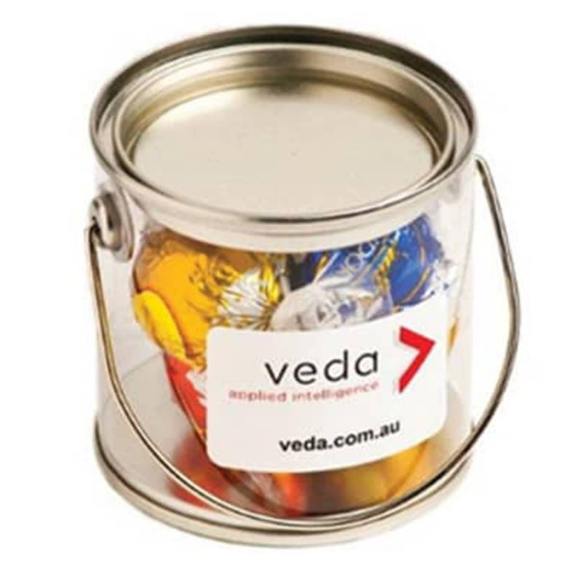 A small silver PVC bucket filled with colourful Lindt chocolate balls. The bucket features a handle and a logo label.