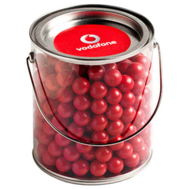 A clear bucket filled with vibrant red chocolate balls, featuring a lid and a metal handle.
