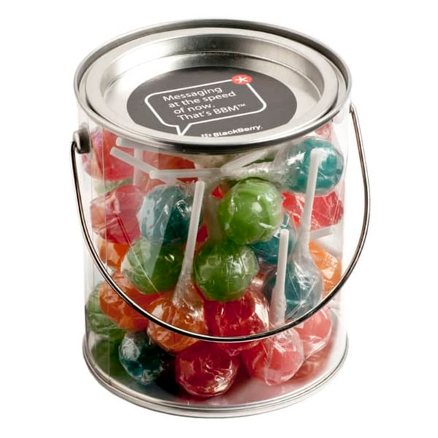 A transparent PVC bucket filled with colourful Chuppa Chups lollipops in various flavours. The bucket has a metal handle.