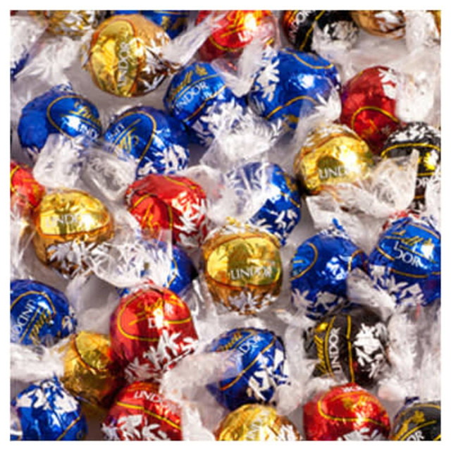 A collection of Lindor chocolate balls in red, blue, gold, and black wrappers, with some featuring a festive design.
