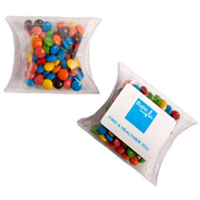A pillow pack containing M&Ms in various colours, including red, blue, yellow, green, brown, and orange.
