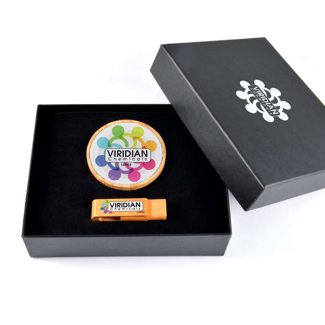 A black gift box containing a circular coaster and a wooden flash drive, both featuring colorful designs and branding.