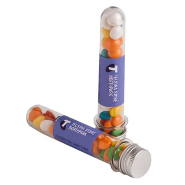 A test tube filled with colourful chewy fruit sweets, featuring a silver cap and a logo on the side.