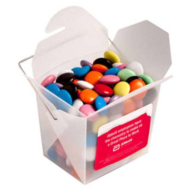 A frosted noodle box filled with colourful chocolate beans, featuring a metal handle and a logo on the side.