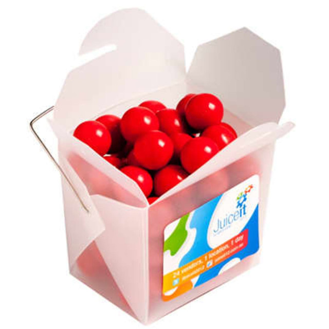 A frosted noodle box containing round orange chocolate drops, with a handle and a colourful logo.