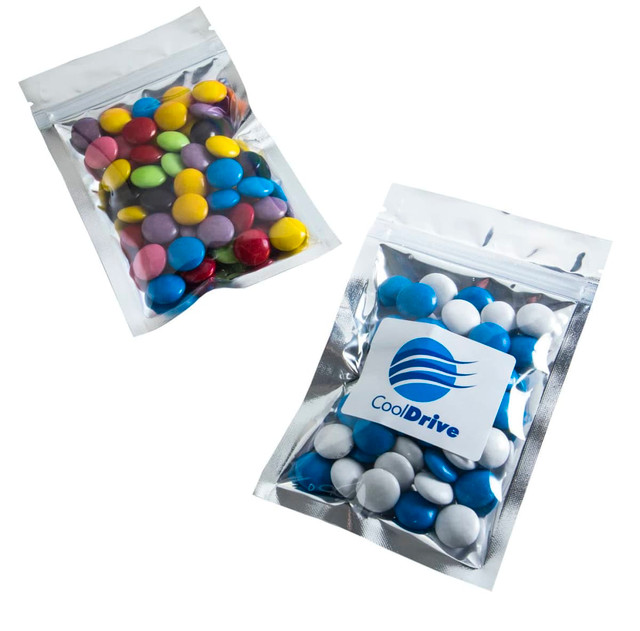 Silver zip lock bags filled with colourful choc beans, featuring a logo on one bag.