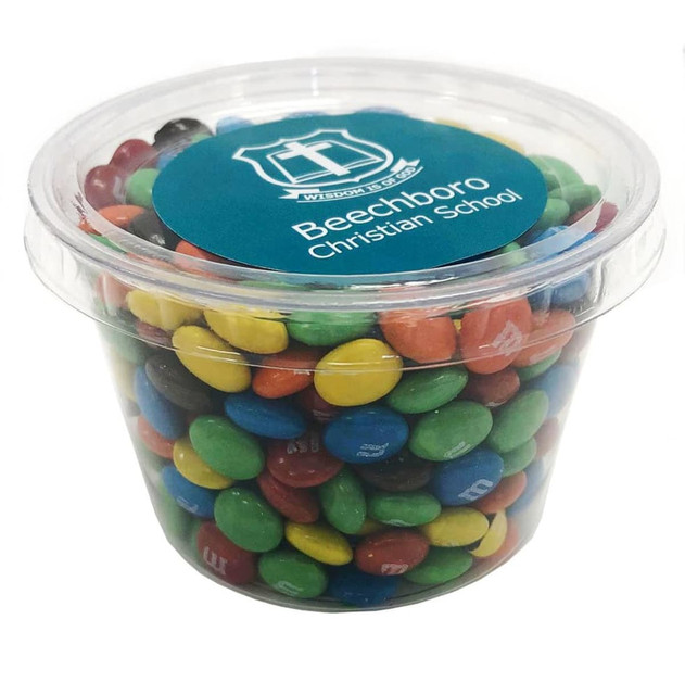 A tub filled with brightly coloured M&Ms, featuring blue, green, yellow, red, and orange candies. The tub has a logo.