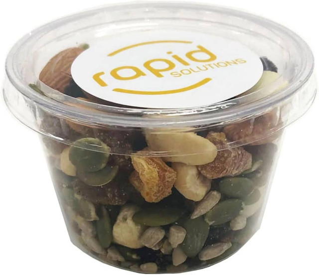 A clear tub filled with a mix of nuts, seeds, and dried fruits. The tub features a logo on the lid.