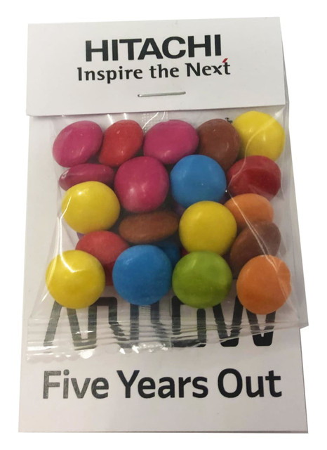 A bag of multi-coloured chocolate beans, featuring pink, blue, yellow, orange, and brown candies, with branding on the packaging.