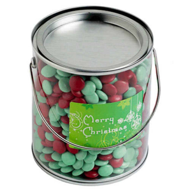A metal bucket filled with red and green chocolate beans, featuring a festive label on the front.